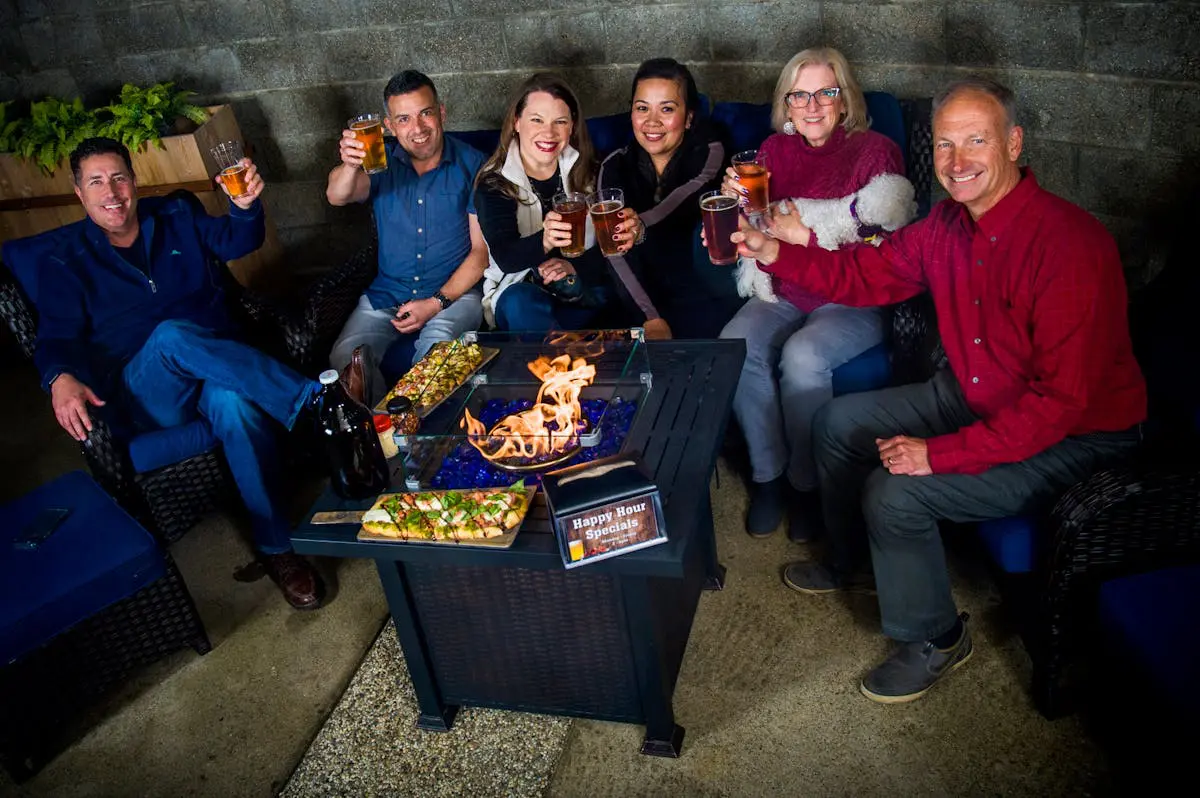 asset 12 Group of friends enjoying drinks and snacks around a fire pit.