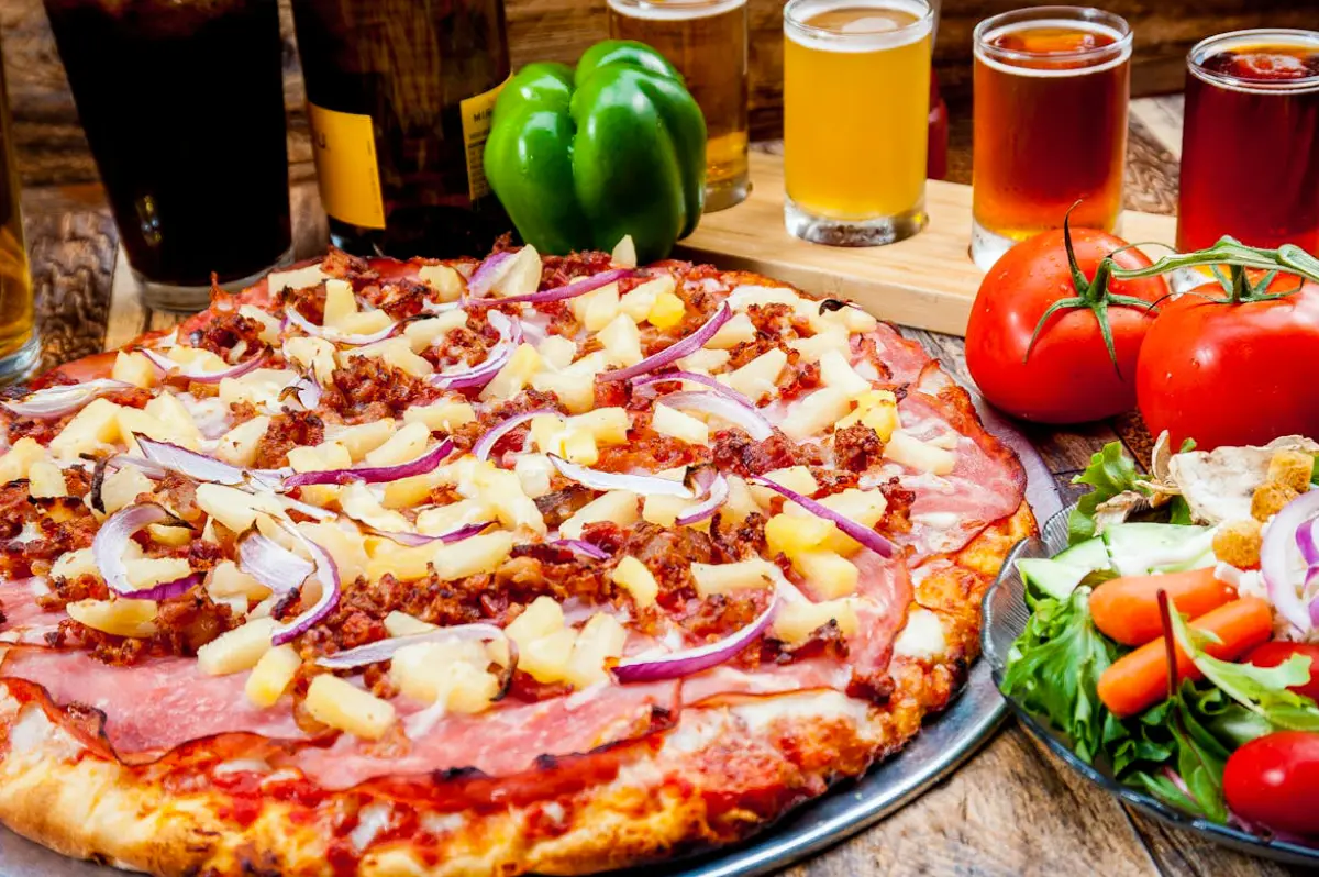 A freshly baked pizza topped with onions, chicken, and ham.
