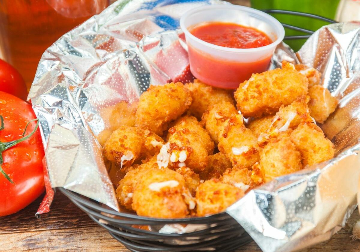 asset 13 A basket of crispy fried cheese balls with a side of red dipping sauce.