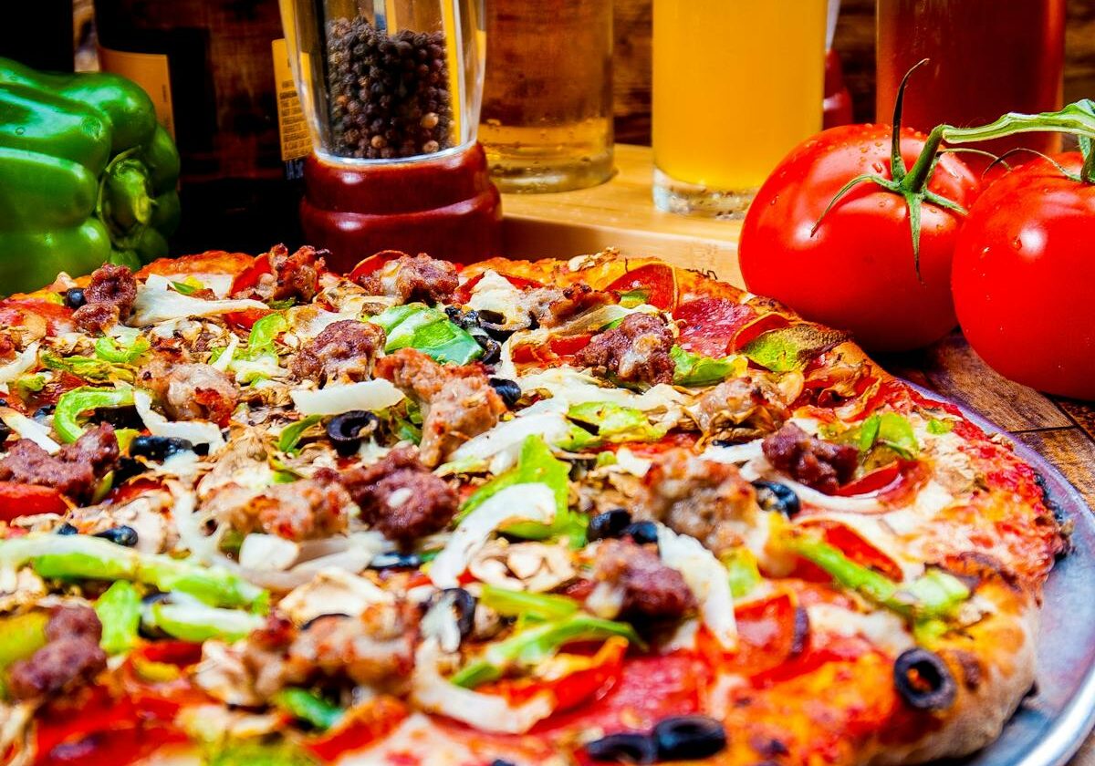 asset 22 A colorful veggie pizza with tomatoes and condiments in the background.