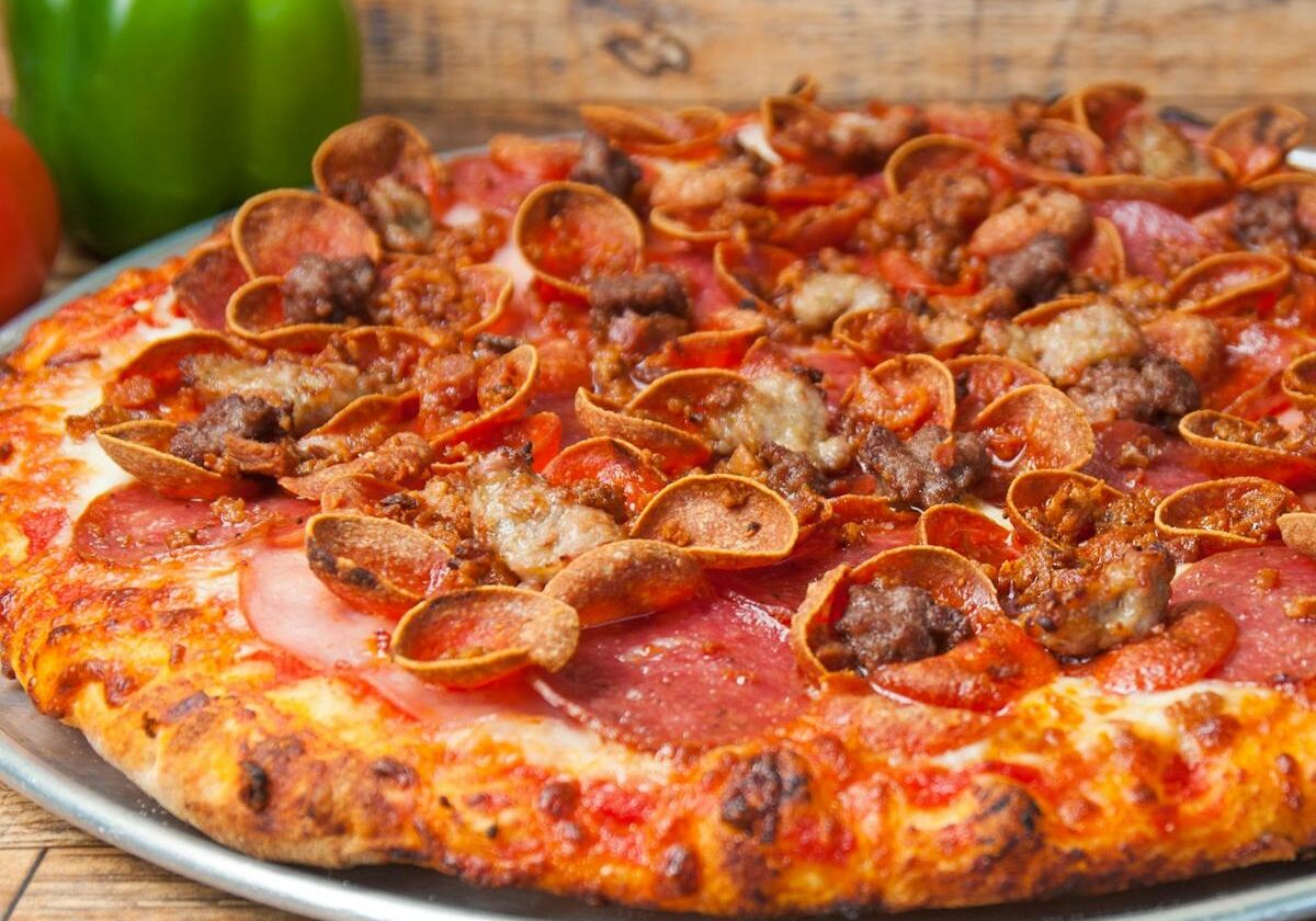 asset 23 A pepperoni pizza with mushrooms and green bell pepper in the background.