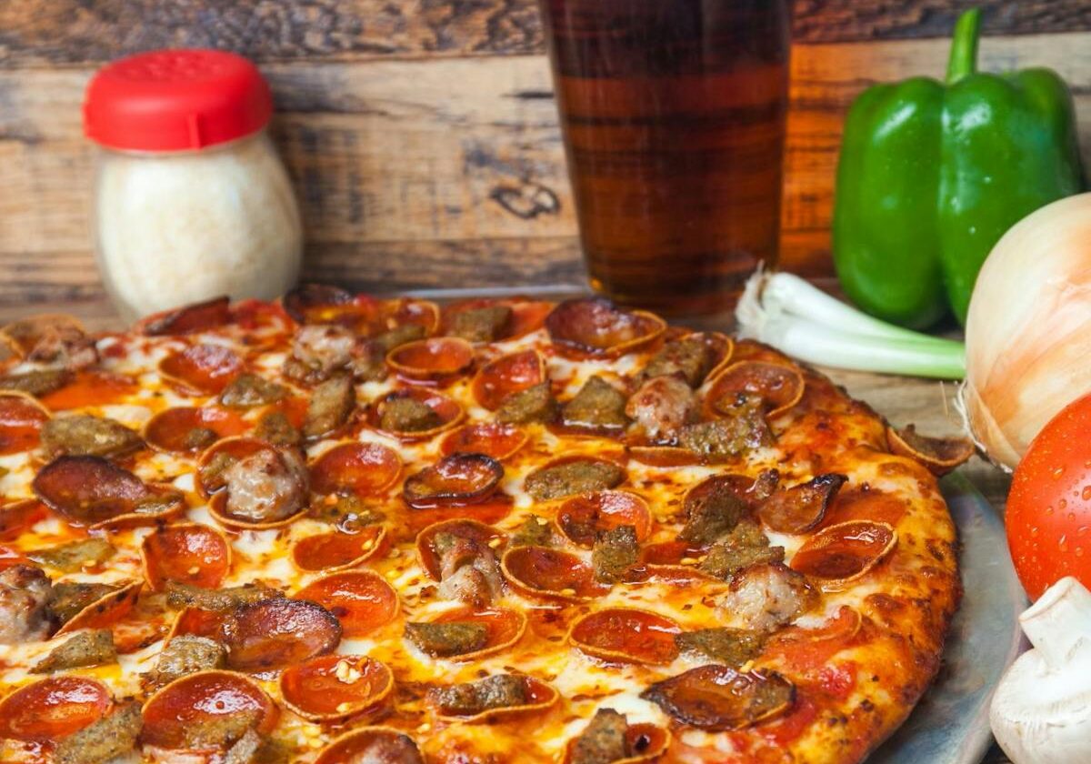 asset 24 A pepperoni pizza with a glass of beer and fresh vegetables.