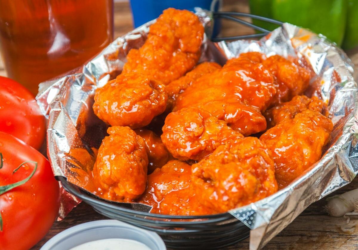 asset 3 A basket of saucy buffalo wings with dipping sauce.
