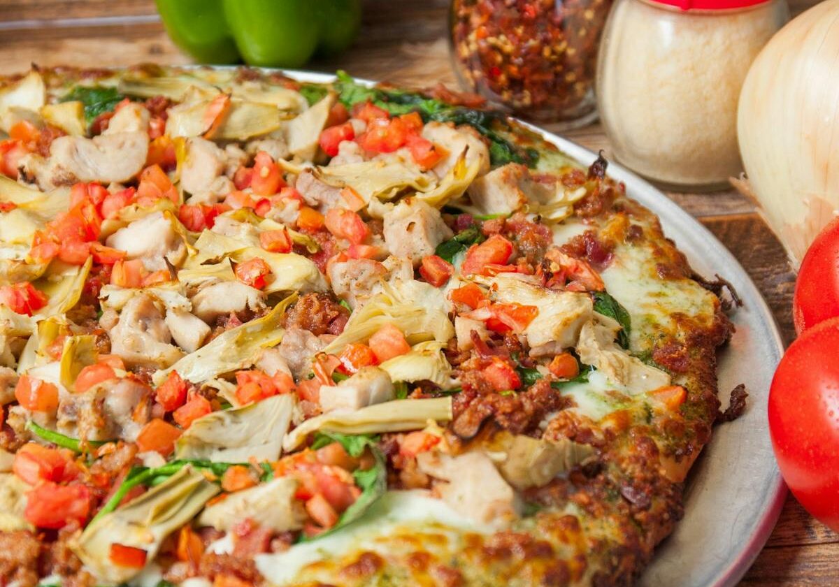 asset 30 A freshly baked pizza topped with chicken, tomatoes, and green peppers.
