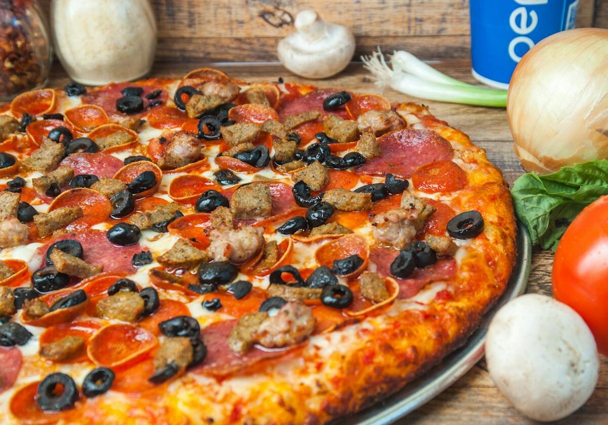 asset 32 A pepperoni pizza topped with olives on a metal tray.