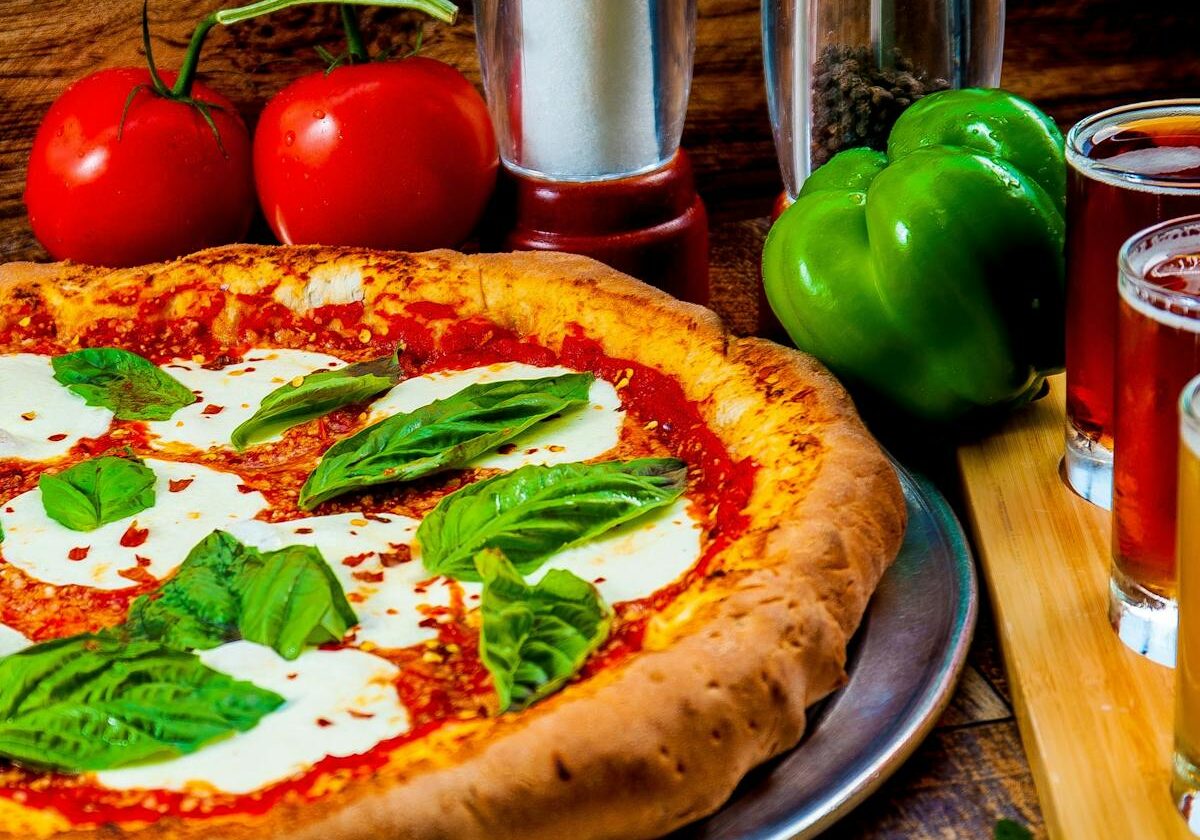asset 34 A Margherita pizza with fresh basil and tomatoes on a wooden table.