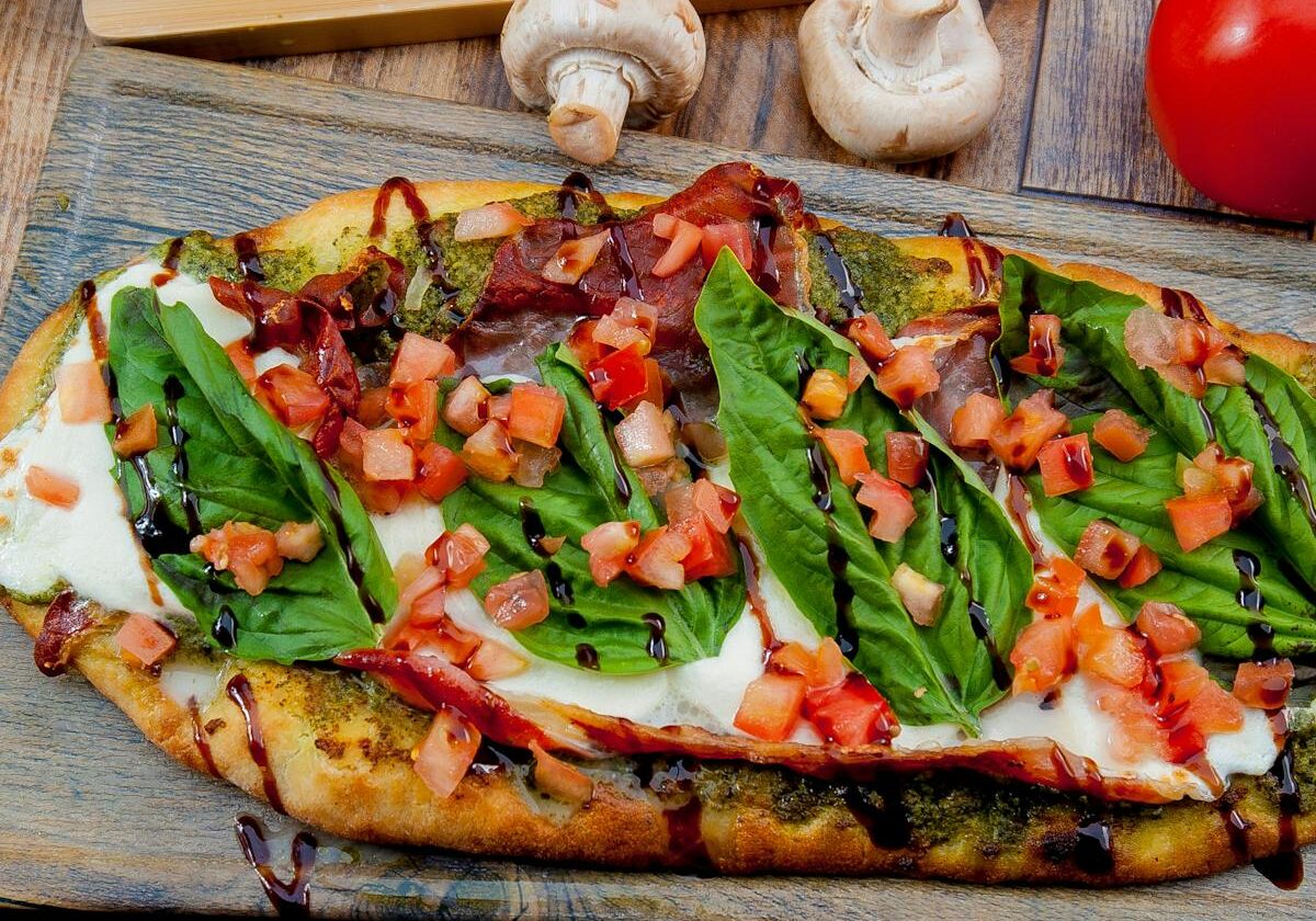 asset 38 A rectangular pizza topped with fresh arugula, mushrooms, and tomatoes.