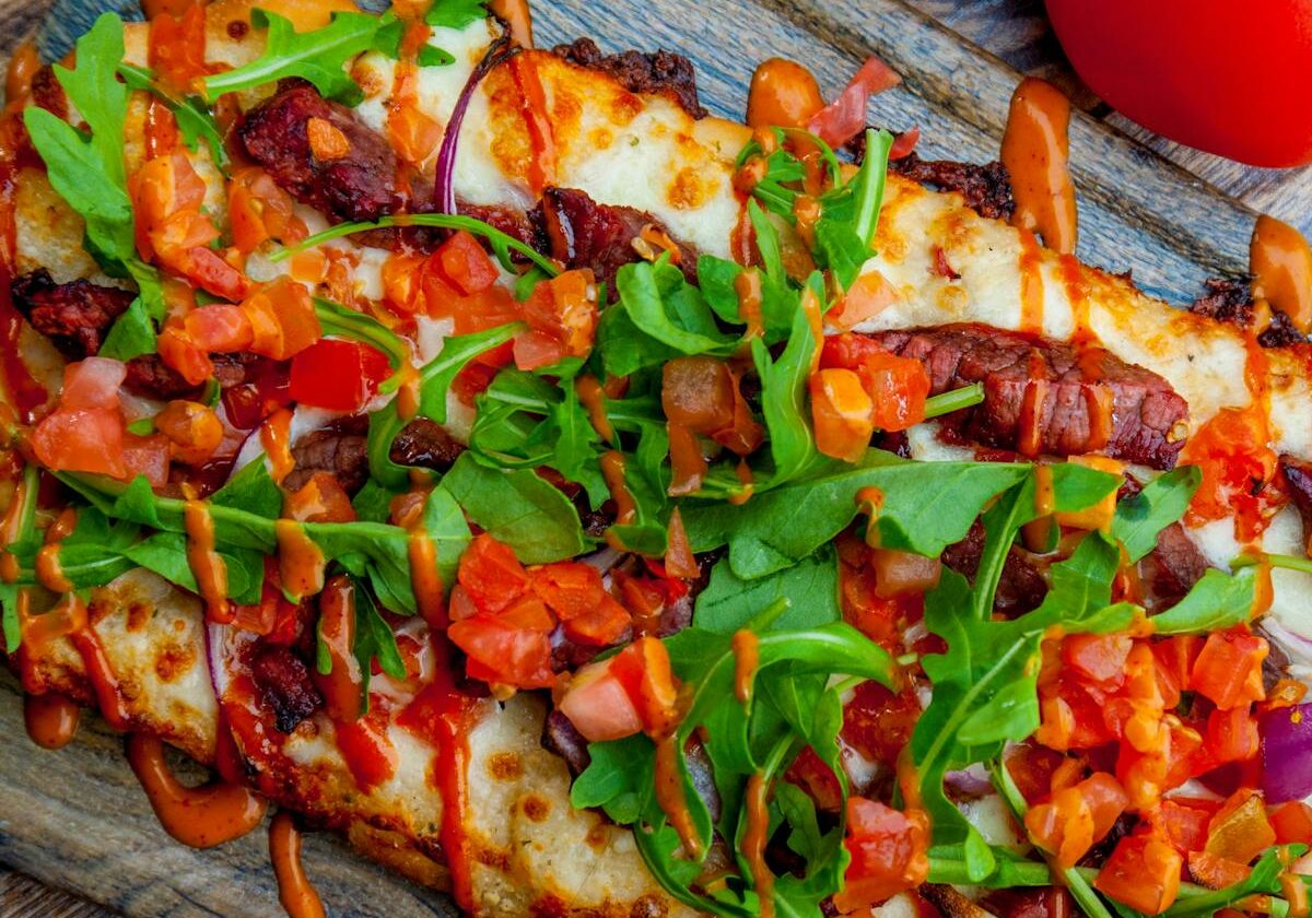 asset 39 Loaded cheesy bread topped with bacon, tomatoes, and greens.