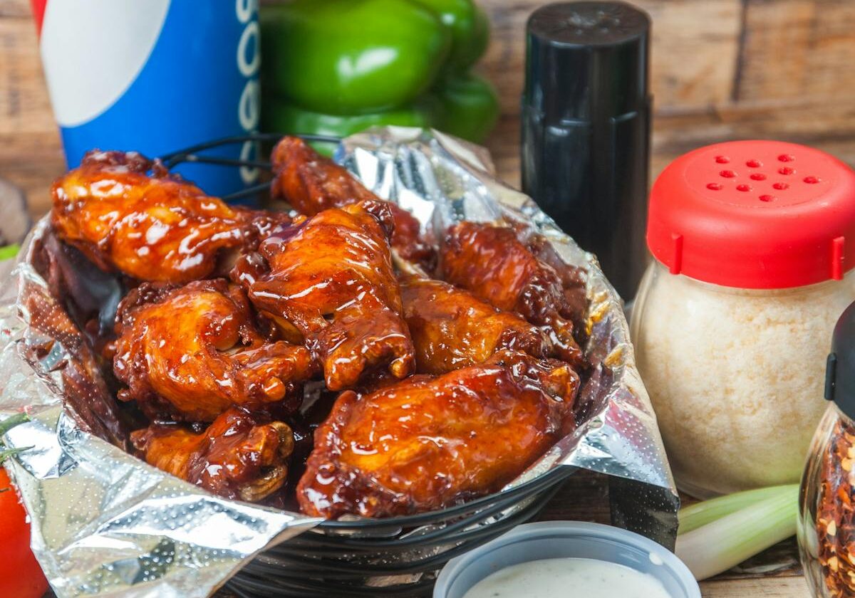 asset 4 A basket of glazed chicken wings with dipping sauce and drinks.