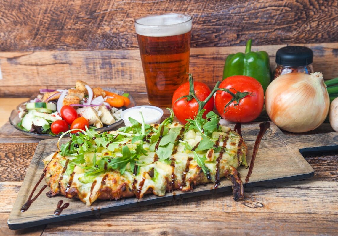 asset 41 Grilled flatbread topped with greens, served with a glass of beer.