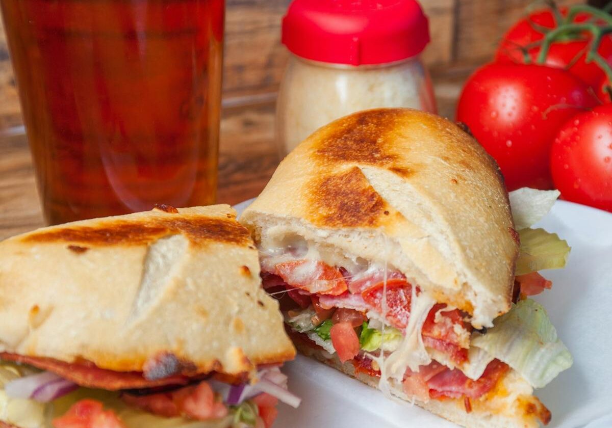 asset 49 A sandwich with bacon, egg, and tomato on a white plate.