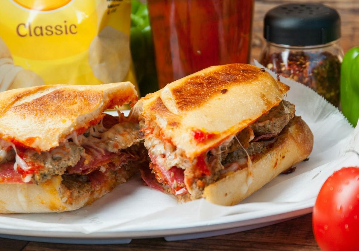 asset 52 A toasted sandwich with melted cheese and beef served with Lay's chips and a drink.