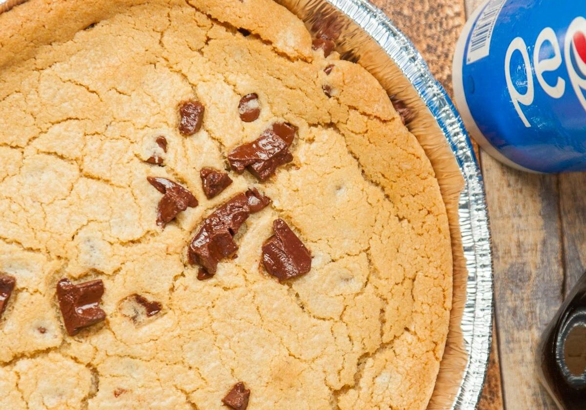 asset 55 A chocolate chip cookie pie with a can of Pepsi and a spoon.