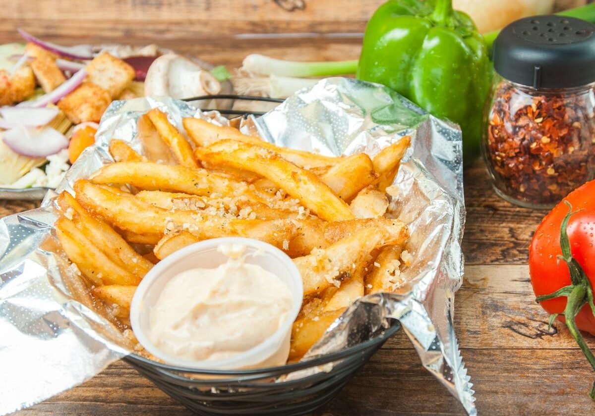 asset 9 A basket of seasoned fries with dipping sauce and fresh vegetables.
